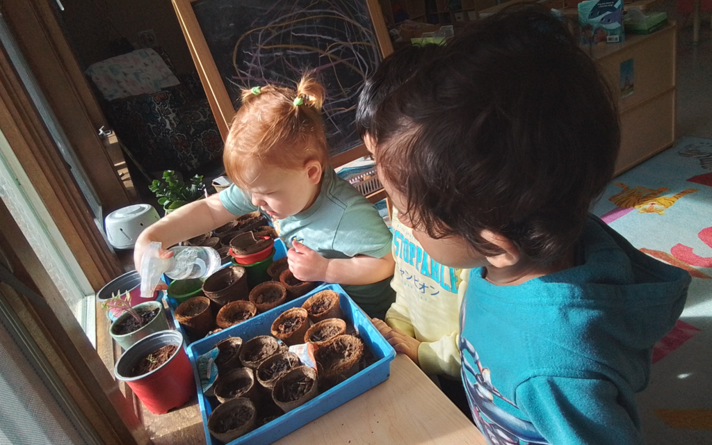 Two toddlers grow plants in nature